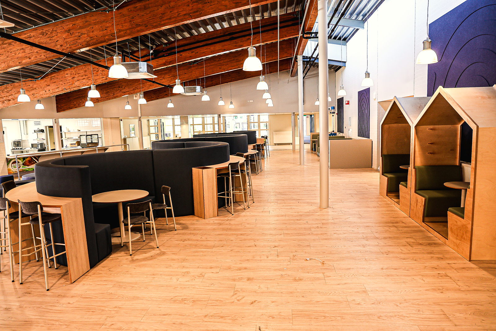 De aula van SAM College met zitbanken, huisjes en de open keuken