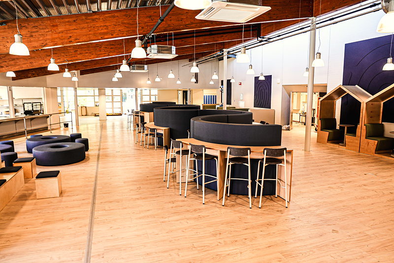 Zithoek in de aula van SAM College met ronde poefs en hoge tafels